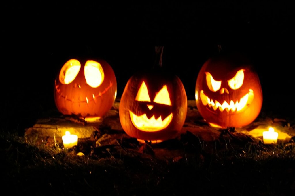 Três abóboras de Halloween iluminadas à noite; fotografia ilustrativa
