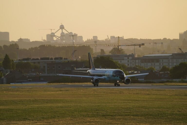 Aeronave taxiando em pista do Aeroporto de Bruxelas, com o Atomium ao fundo