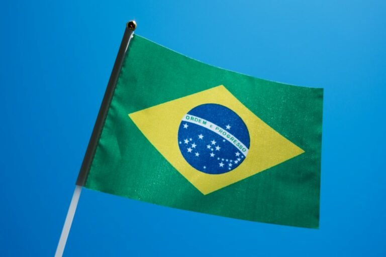 Bandeira do Brasil ao ar livre sob céu azul; fotografia ilustrativa