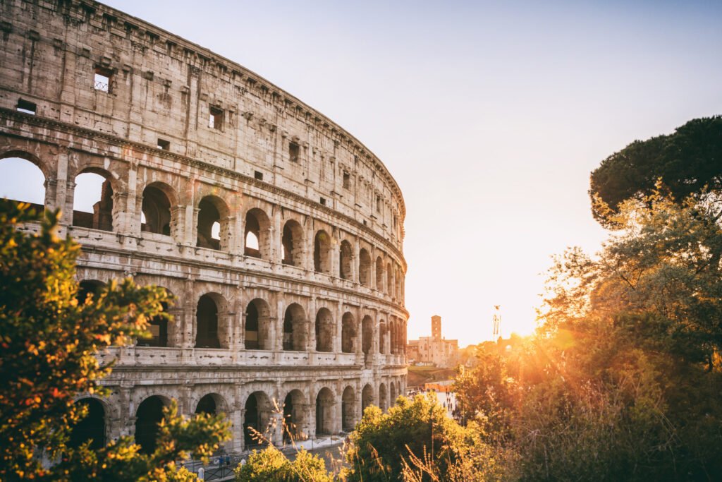 Coliseu de Roma ao pôr do sol, cercado por árvores