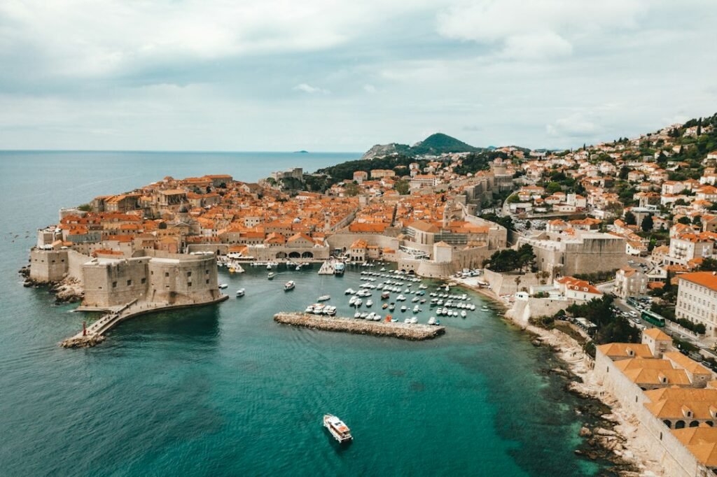 Vista aérea do centro histórico de Dubrovnik, suas muralhas e o mar Adriático.