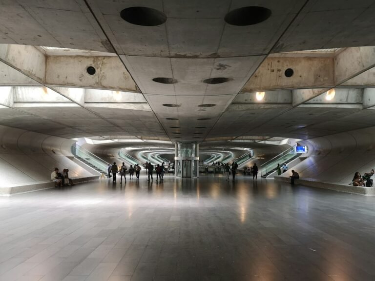 Área interna da Estação do Oriente, em Lisboa, com escadas rolantes e passageiros