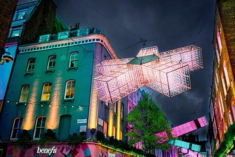 Instalação luminosa colorida suspensa sobre uma rua de Londres à noite