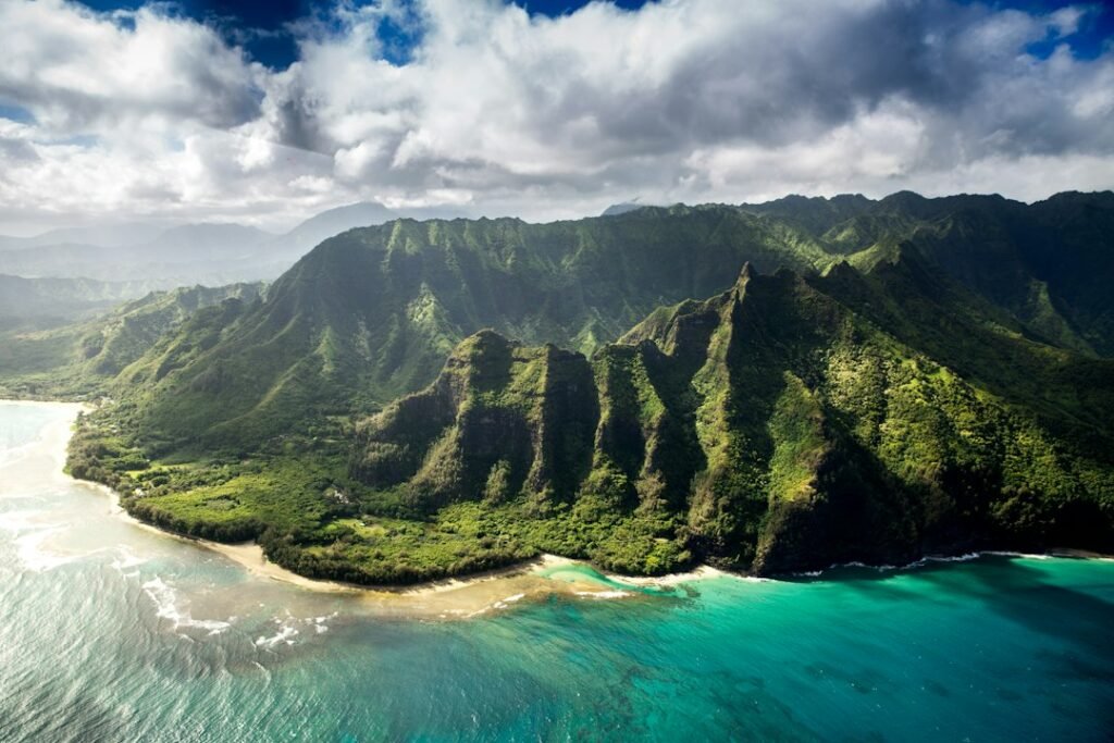 Montanhas verdes da costa de Kauai, no Havaí, diante do oceano.