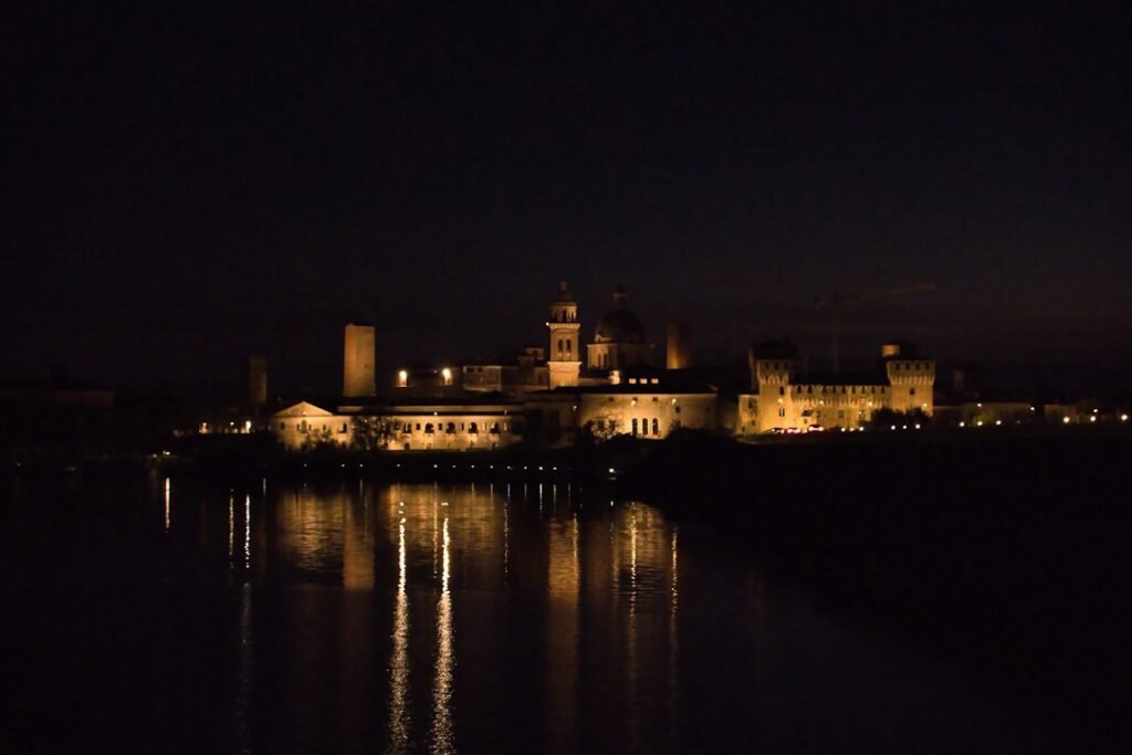 Centro histórico de Mantova iluminado à noite e refletido nas águas