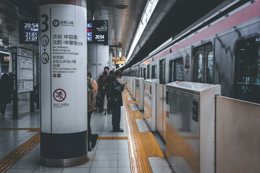 Trem e passageiros na plataforma da linha Fukutoshin, com sinalização de destinos