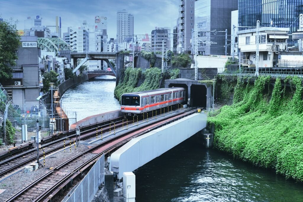 Trem urbano vermelho e branco circula por Tóquio ao lado de um canal